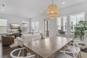 A modern living room with a dining area, white furniture, and a large window with blinds. - Seasonally Pet Friendly! 6-Seater Golf Cart! Pool&Beach!-Gulfview Getaway on 30A (Santa Rosa Beach)