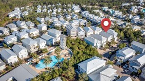 Un quartier résidentiel comprenant plusieurs maisons, une piscine centrale et un repère rouge indiquant l’emplacement.
