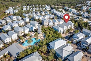 A residential area with multiple houses, a central swimming pool, and a red location marker.