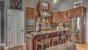 Une cuisine dotée de meubles en bois, d’appareils électroménagers en acier inoxydable et d’un îlot central avec des sièges de bar.