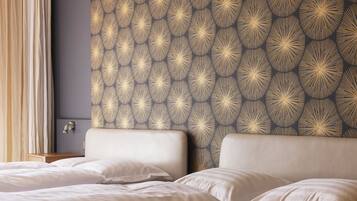 Habitación de hotel con dos camas, un cabecero de diseño oscuro y una mesita de noche con lámpara.
