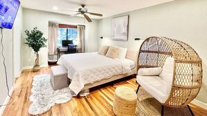 A bedroom with a bed, a hanging chair, a desk, and a television. - Family Retreat • Pool • Air Hockey • King Suite (Chico)
