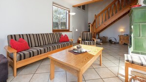 A living room with a sofa, armchair, wooden coffee table, and a staircase. - Holiday Home in Groebming near Ski Slopes (Gröbming)