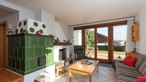 A cozy living room with a fireplace, a sofa, a wooden coffee table, and a sliding glass door leading to a patio. - Holiday Home in Groebming near Ski Slopes (Gröbming)