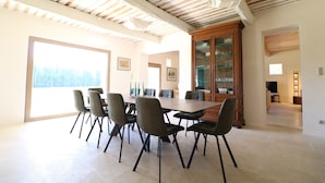 A dining area with a large table and chairs, a wooden cabinet, and a view through a glass door. - Spacious and quiet farmhouse in Isle sur la Sorgue (L'Isle-sur-la-Sorgue)