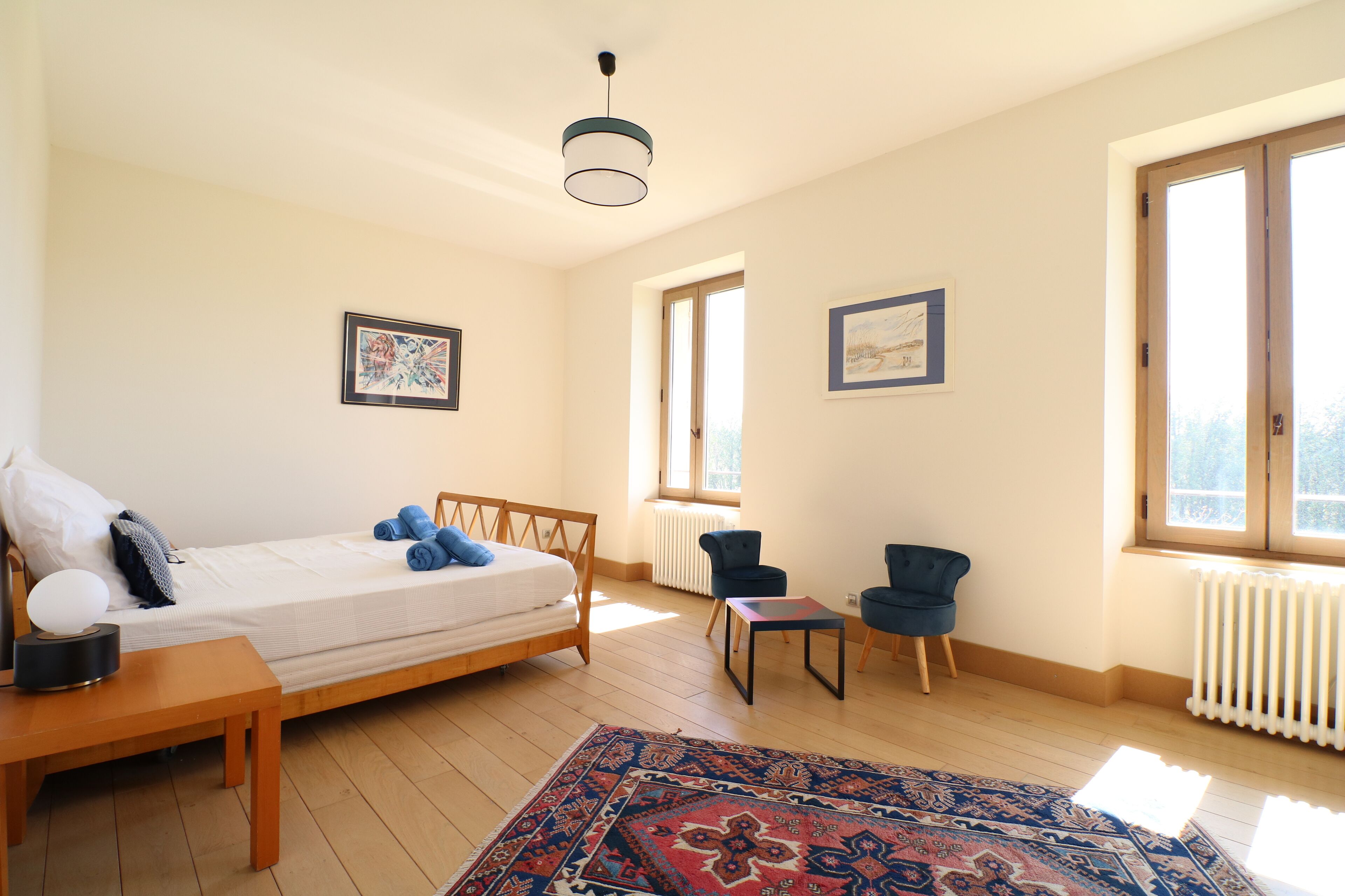 A bedroom with a bed, two chairs, a table, and a rug.