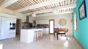 A modern kitchen with white cabinets, a central island with stools, and a wooden table with chairs. - Spacious and quiet farmhouse in Isle sur la Sorgue (L'Isle-sur-la-Sorgue)