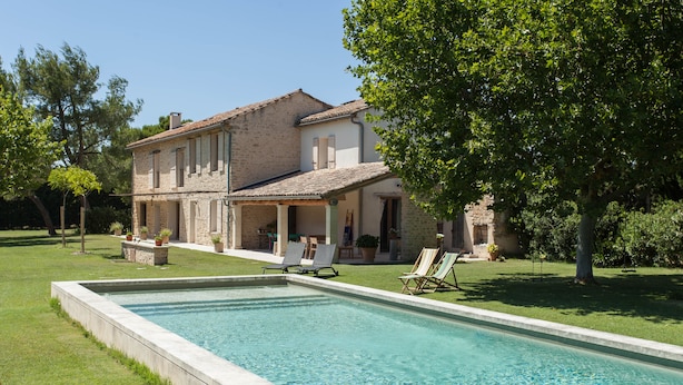 A poolside area with a rectangular pool, lounge chairs, and a house with a tiled roof and stone walls. - Spacious and quiet farmhouse in Isle sur la Sorgue (L'Isle-sur-la-Sorgue)
