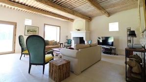 A spacious living room with a high wooden ceiling, a fireplace, a television, and a sofa. - Spacious and quiet farmhouse in Isle sur la Sorgue (L'Isle-sur-la-Sorgue)