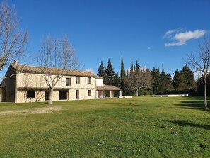 Un edificio in pietra con diverse stanze e una zona salotto esterna coperta.