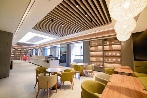 Een modern interieur met een receptiebalie, zithoek en planken met spullen.