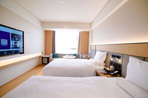 A hotel room with two beds, a TV on the wall, a small table with a lamp, and a window with curtains. - Ji Hotel (Chengdu)