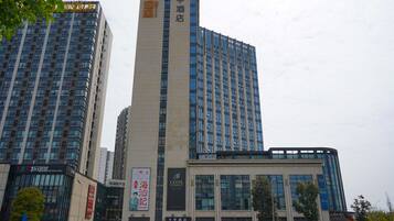 Um hotel com uma placa vertical chamativa, várias janelas e uma fachada moderna.