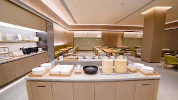 Restaurante moderno com ilha central, mesas de madeira e uma variedade de pratos e utensílios.