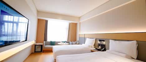 A hotel room with two beds, a television, a bedside table, and a window with curtains.