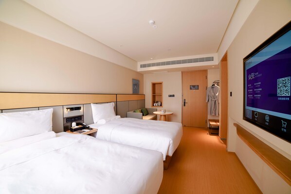 A hotel room with two beds, a bedside table, a small table with a cup, and a wall-mounted TV displaying a QR code. - Ji Hotel (Chengdu)