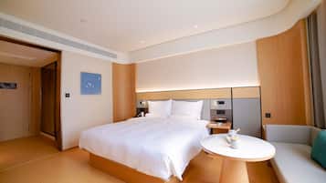 A hotel room with a large bed, bedside tables, a seating area, and a view of the outside.