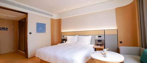 A hotel room with a large bed, bedside tables, a seating area, and a view of the outside.