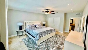 A bedroom with a bed, bedside tables, a ceiling fan, and a patterned rug. - Cozy vacation home 5 mins from downtown!!! (Sarasota)