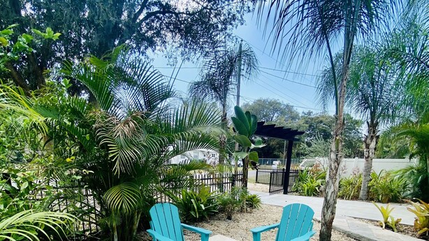 A patio area with four turquoise Adirondack chairs arranged around a square table with a star design. - Cozy vacation home 5 mins from downtown!!! (Sarasota)