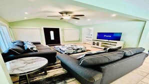 A living room with a sofa set, a coffee table, a TV, and a ceiling fan. - Cozy vacation home 5 mins from downtown!!! (Sarasota)
