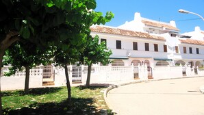 A street with white buildings, a tree, and a clear blue sky.