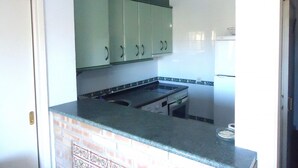 A compact kitchen with green cabinets, a black countertop, and a white refrigerator.