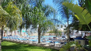A pool area with lounge chairs and palm trees.