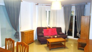 Una sala de estar con un sofá, una mesa de centro de madera, un mueble de madera y una mesa de comedor con sillas.