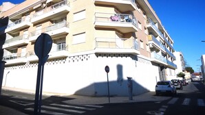 Un edificio residencial de varios pisos con balcones, un parquímetro y una señal de prohibido estacionar.