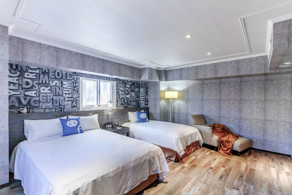 A hotel room with two beds, a large mirror, and a wall with text.