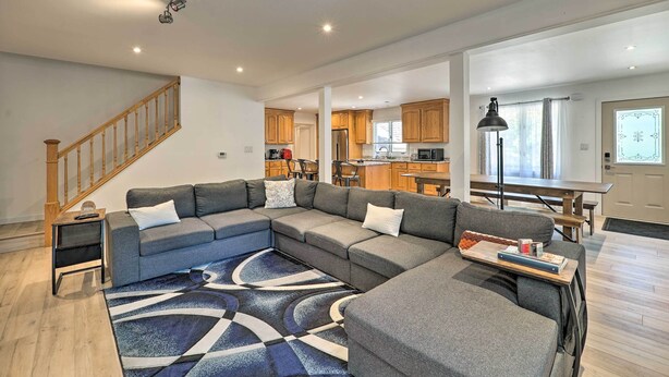 Ein modernes Wohnzimmer mit einem Ecksofa, einem kleinen Beistelltisch und einem gemusterten Teppich.