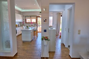 Une cuisine moderne avec des meubles blancs, un îlot central et un coin repas avec des chaises.