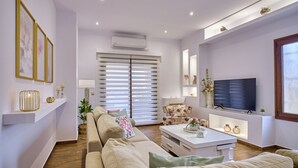 Een moderne woonkamer met een bank, salontafel, televisie en decoratieve objecten.