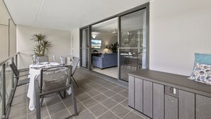Ein moderner Balkon mit Esstisch, Stühlen und Blick ins Wohnzimmer.