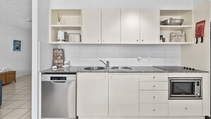Eine moderne Küche mit weißen Schränken, einer Spüle, einem eingebauten Backofen und einem Geschirrspüler.