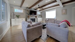 A spacious living room with a fireplace, a large sofa set, and a stone accent wall. - 9 bdrm home, sleeps 26 w/ hot tub/gym/theatre/bar (Surrey)