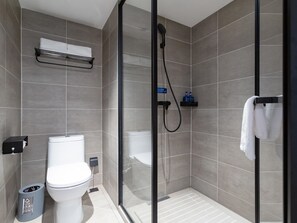 A modern bathroom with a toilet, a glass shower enclosure, and a towel rack. - Hanting Hotel (Beijing)