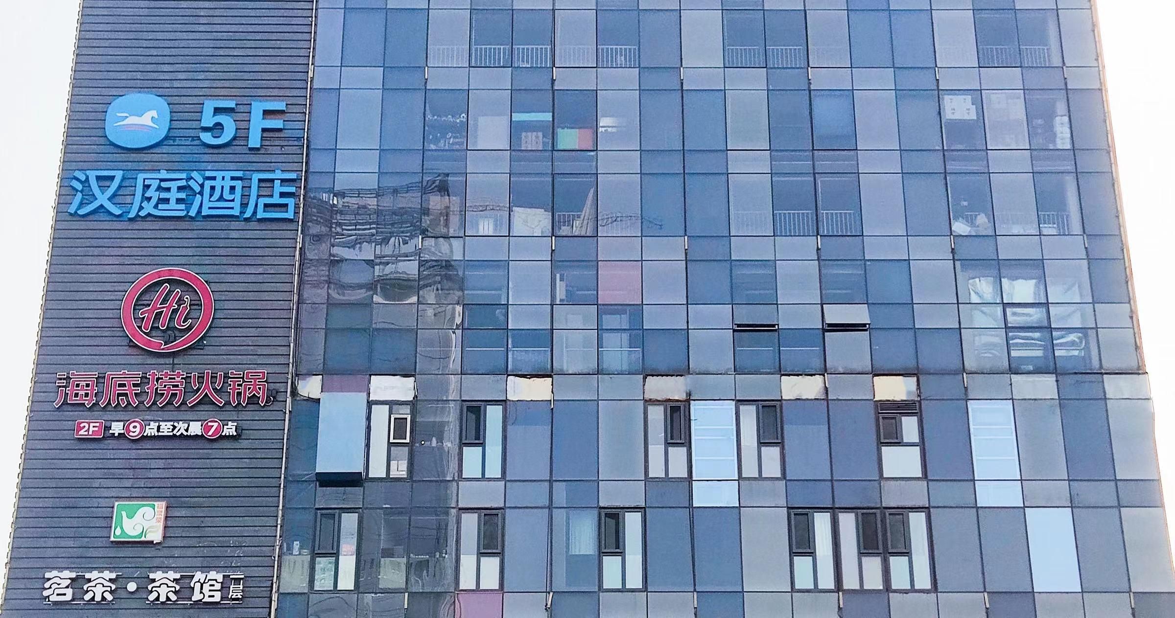 Un bâtiment moderne avec une enseigne indiquant un hôtel appelé « 5F » et une autre enseigne pour « 海底捞火锅 », ce qui laisse supposer qu’il s’agit d’un restaurant.