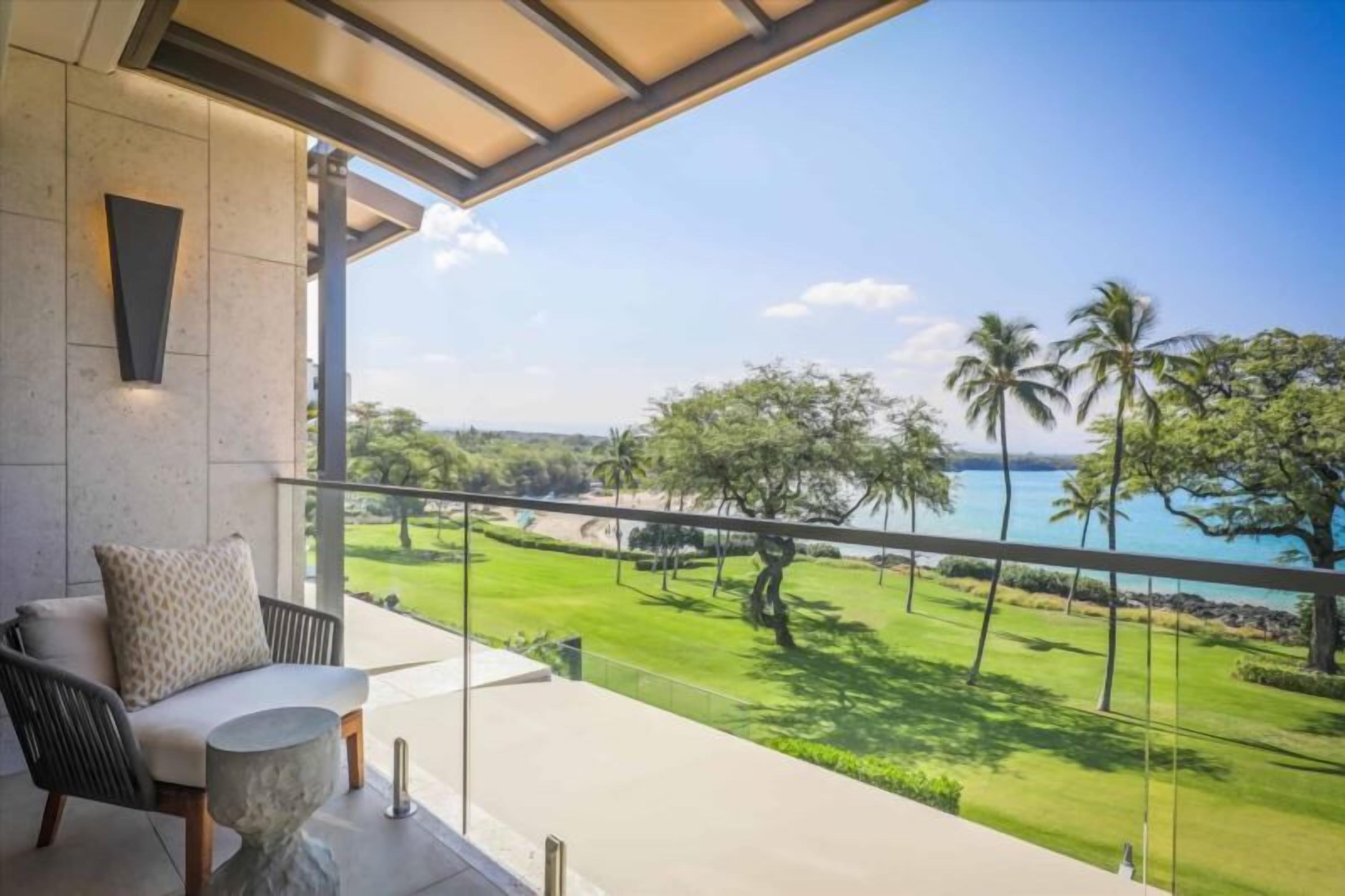 Ein Balkon mit Blick auf einen Golfplatz und Palmen, ein gepolsteter Stuhl und ein kleiner runder Tisch.
