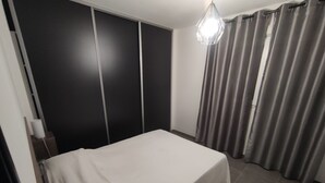 Een slaapkamer met een bed, een kledingkast en gordijnen.