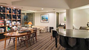 A hotel room with a dining area, a piano, a bookshelf, and a painting on the wall. - La Jolie Motomachi (Hakodate)