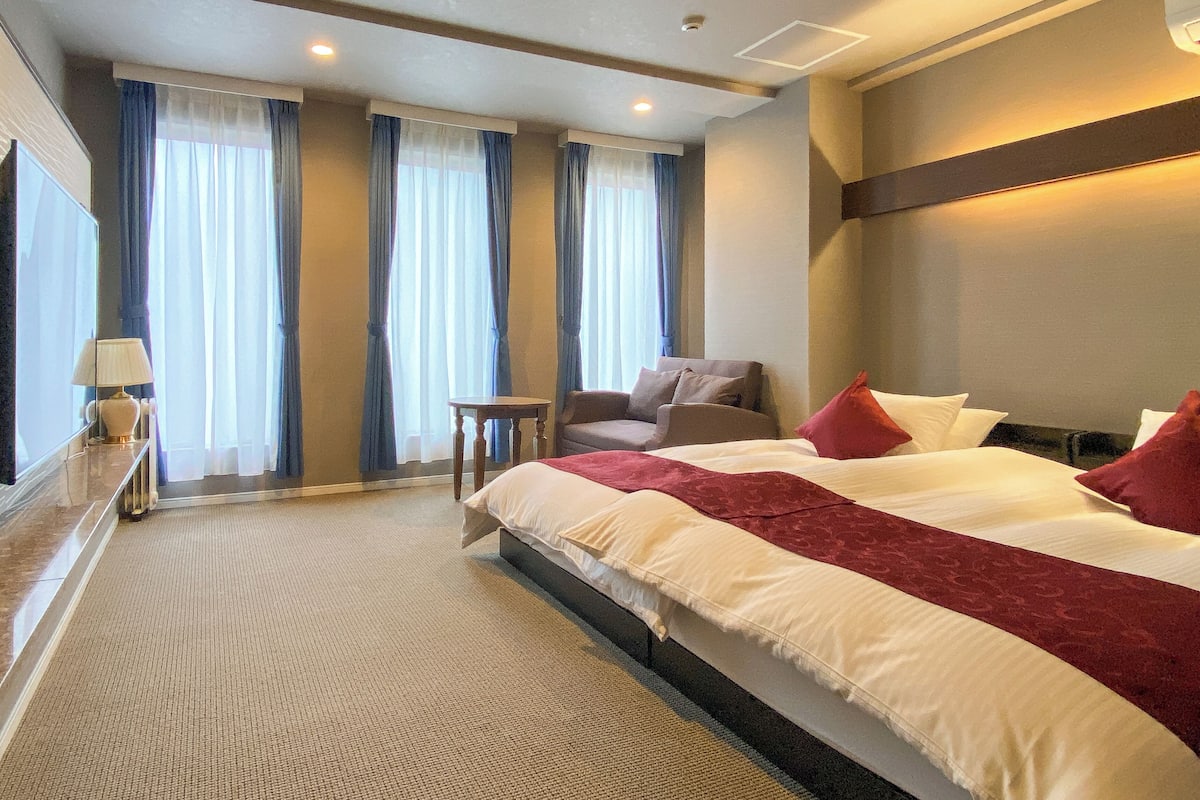 Een hotelkamer met een groot bed, een stoel, een bijzettafeltje en een spiegel.