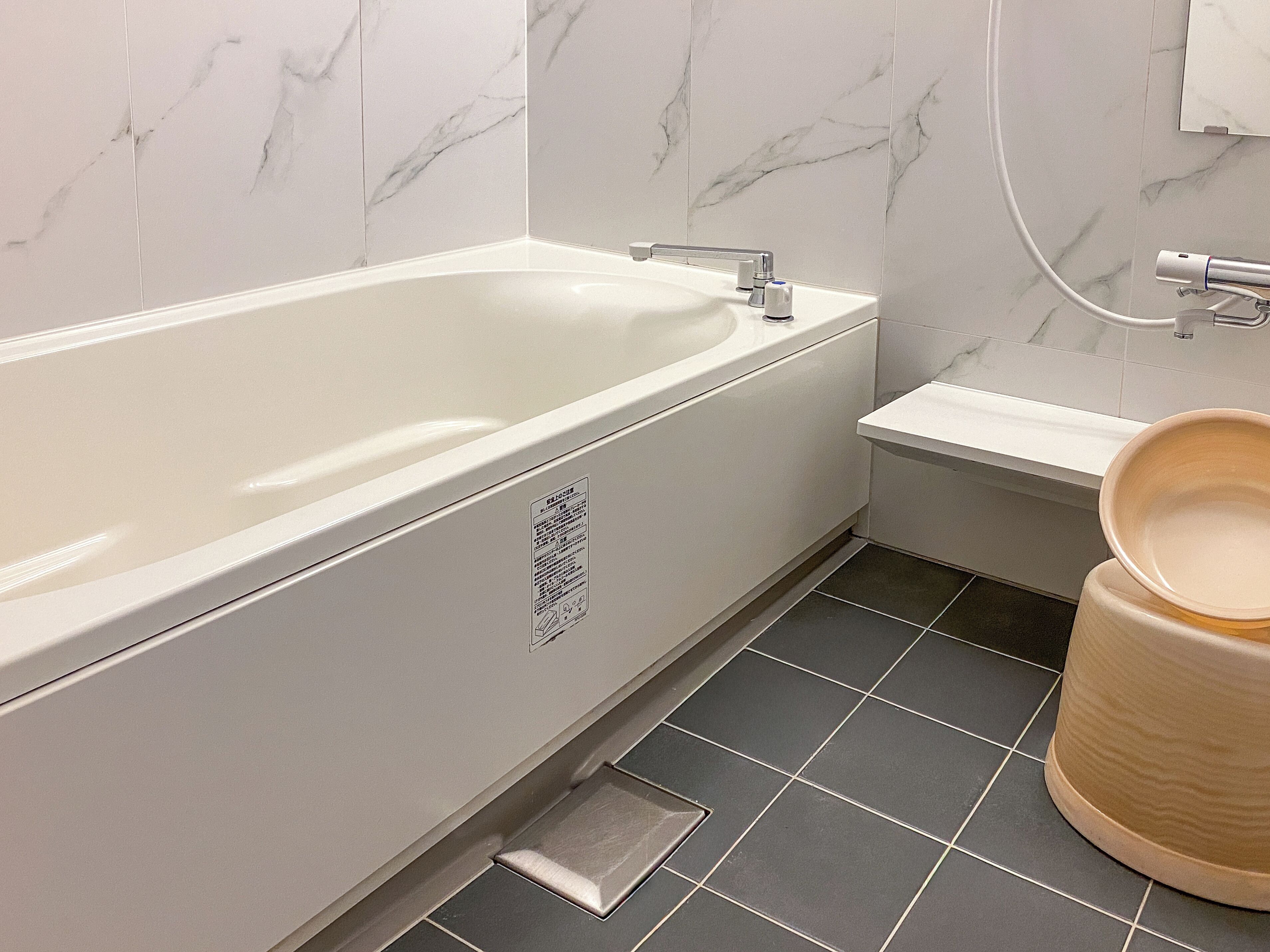 A bathroom with a white bathtub, a small sink, and a toilet.