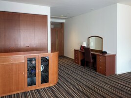 Una habitación de hotel con un armario de madera, un escritorio con espejo y una alfombra a rayas.