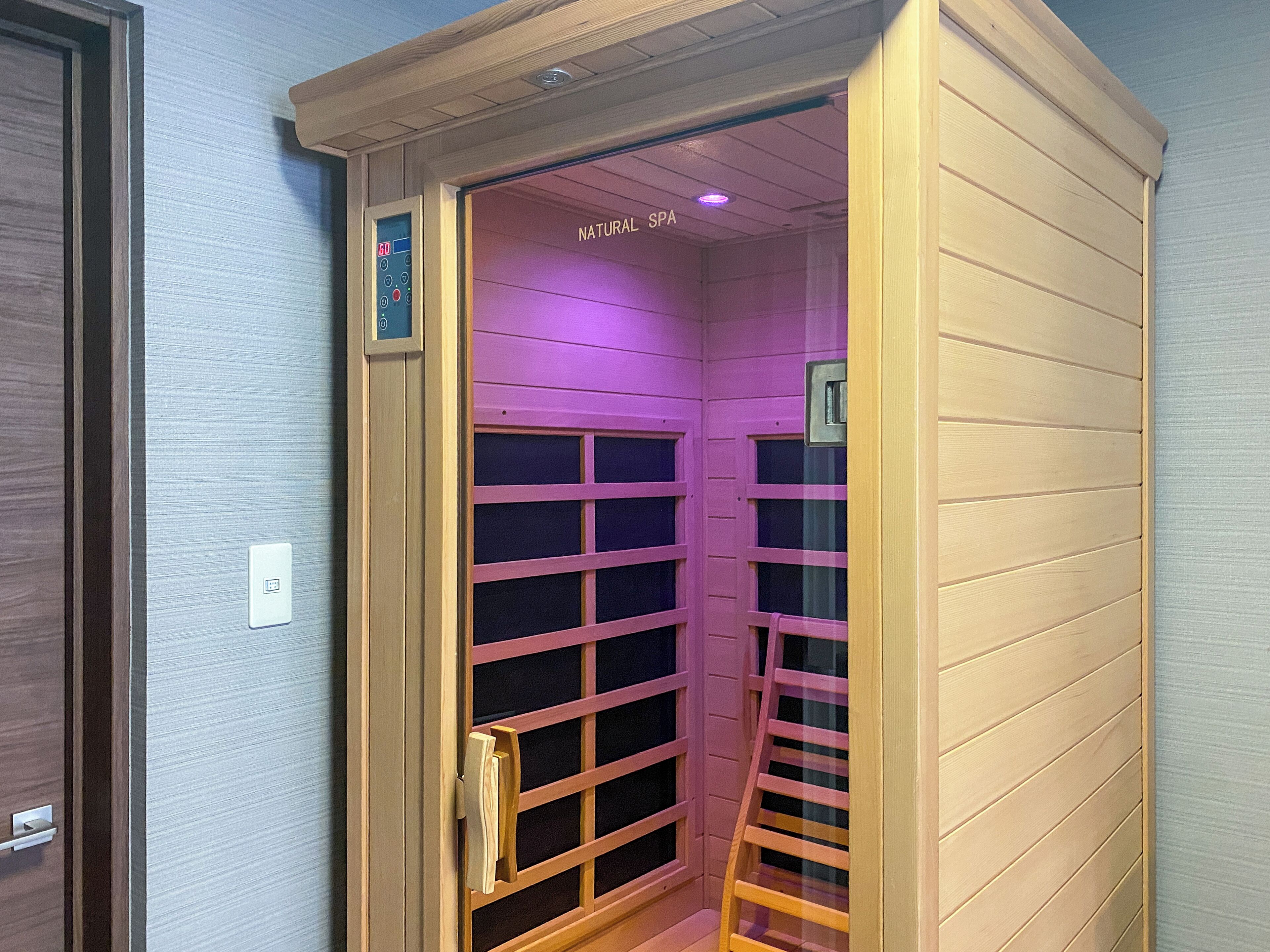Une salle de spa équipée d’un panneau de commande, d’une porte coulissante et d’un panneau indiquant qu’il s’agit d’un spa naturel.