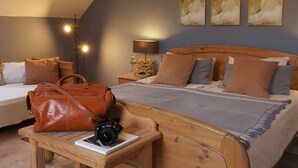 A bedroom with a wooden bed, a nightstand with a lamp, a brown leather bag, and a camera on a table. - Apartment Ostrau | Villa Falkenstein (Bad Schandau)