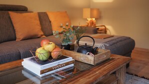 A cozy living room with a wooden coffee table, a stack of books, and a fruit basket. - Apartment Ostrau | Villa Falkenstein (Bad Schandau)