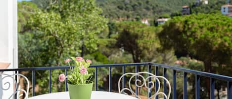 A balcony with a round table and a potted plant.