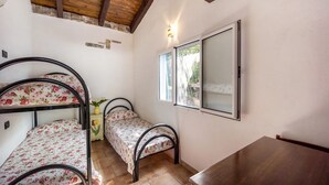 A room with bunk beds, a wooden table, a window with a view, and a wall-mounted mirror.